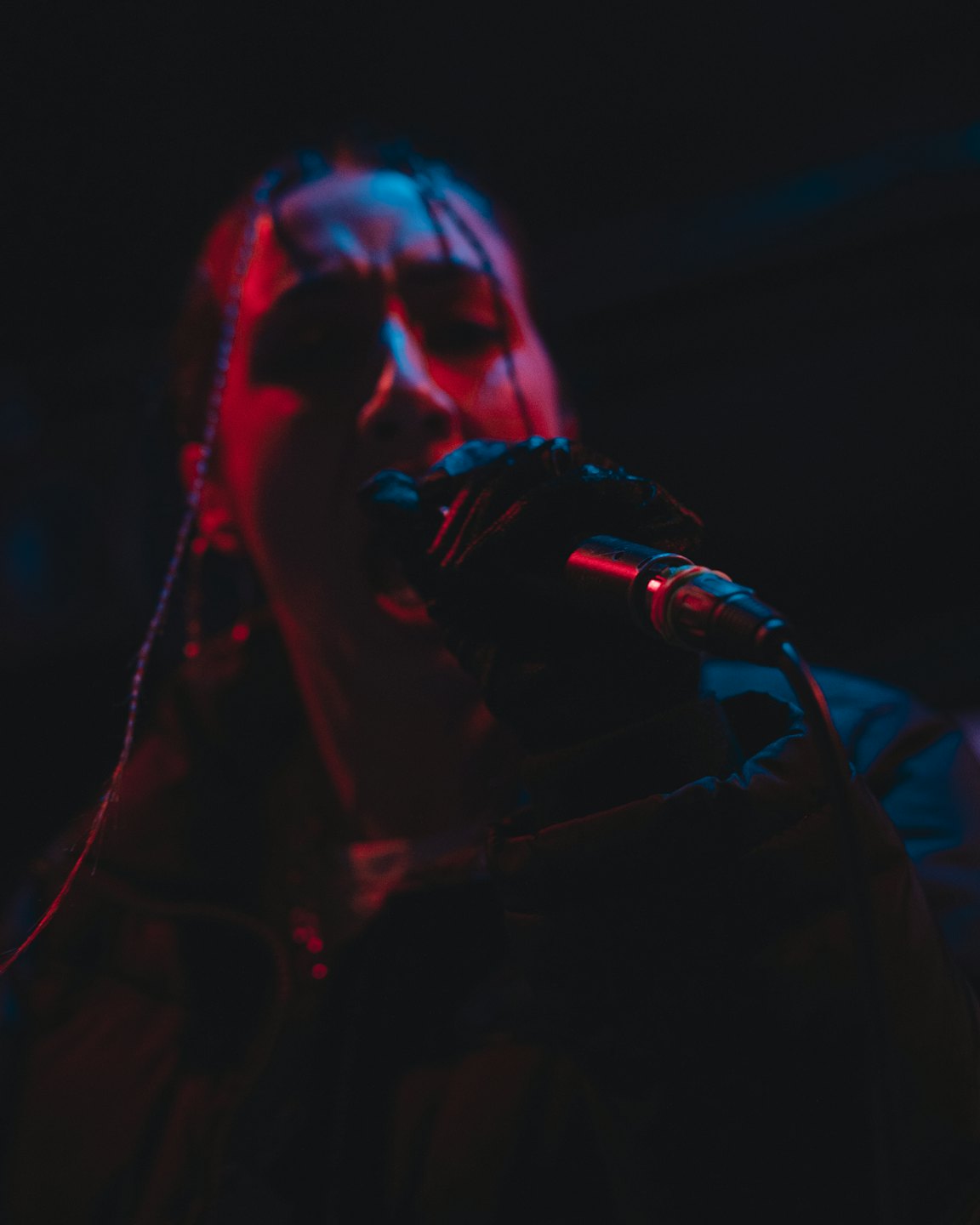 A performer sings passionately into a microphone on stage.